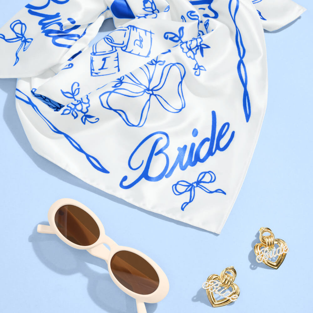 White bandana with blue graphics and 'Bride' text, sunglasses, and heart-shaped earrings on a light blue background