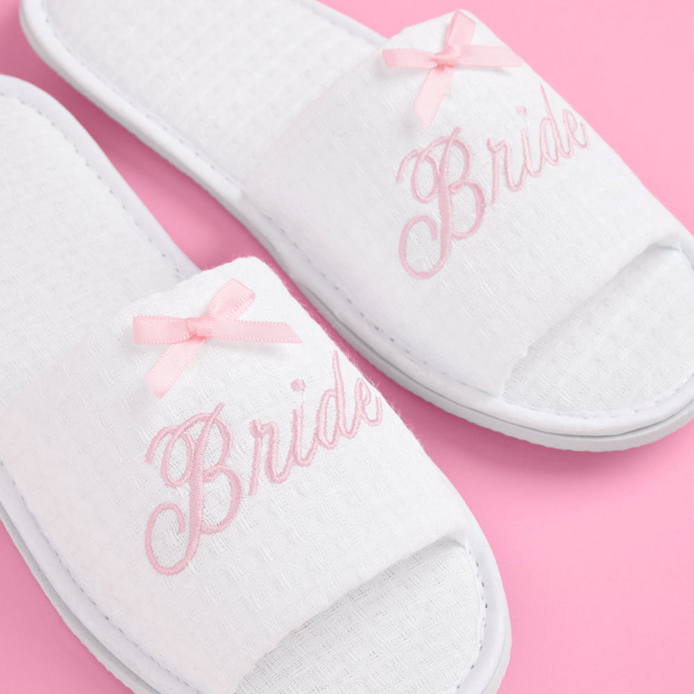 White slippers with 'Bride' embroidery on a pink background