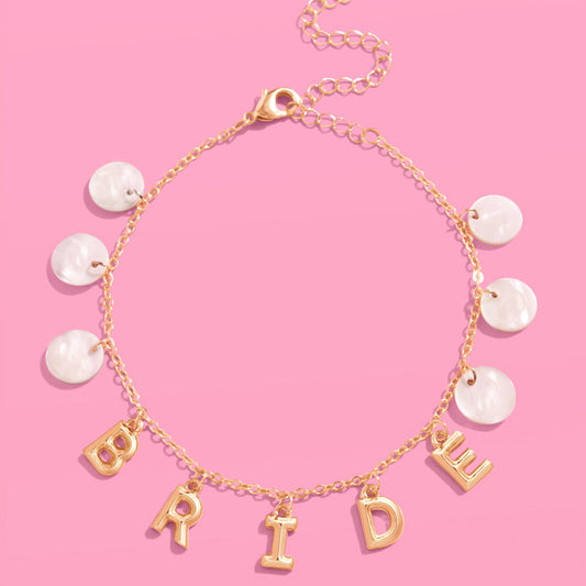 Gold bracelet with 'Bride' charm on a pink background