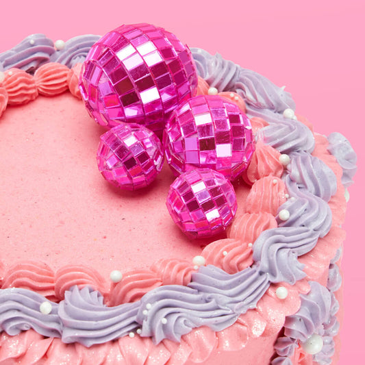 Pink and purple cake with disco balls on a pink background