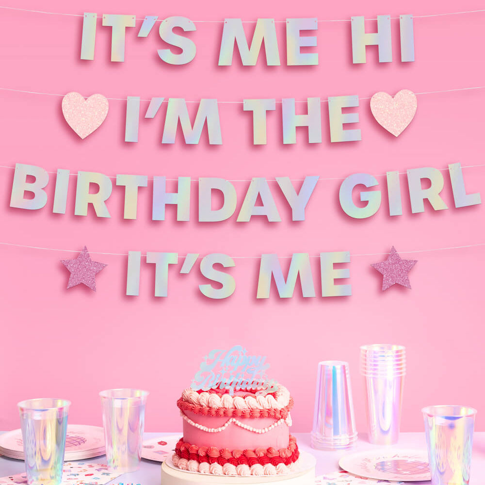 Pink birthday party setup with cake and decorations on a pink background