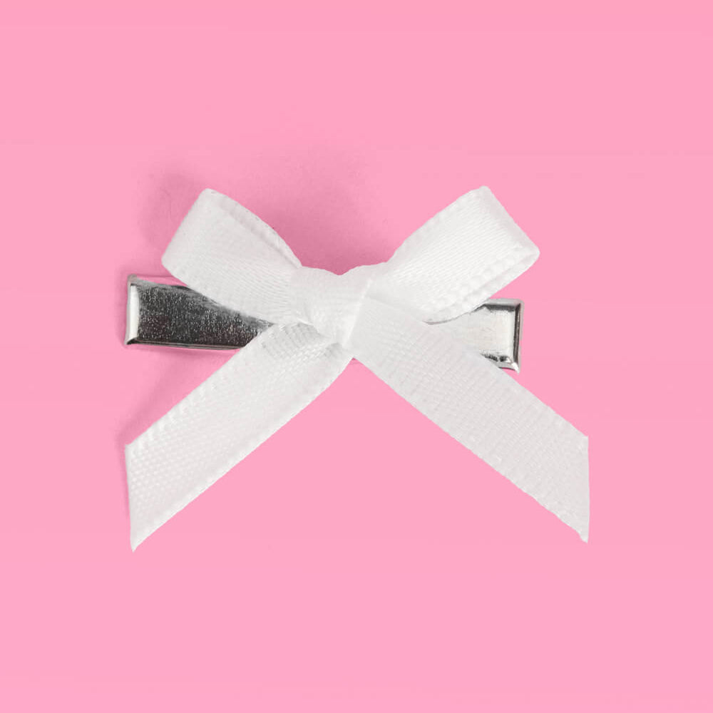 White bow hair clip on a pink background