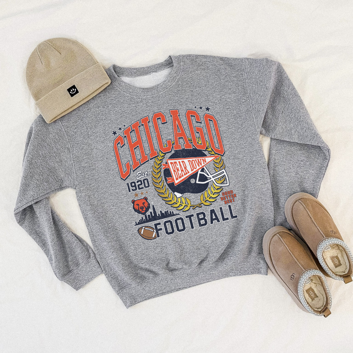 Gray sweatshirt with Chicago football design, beige beanie, and brown shoes on a light gray background