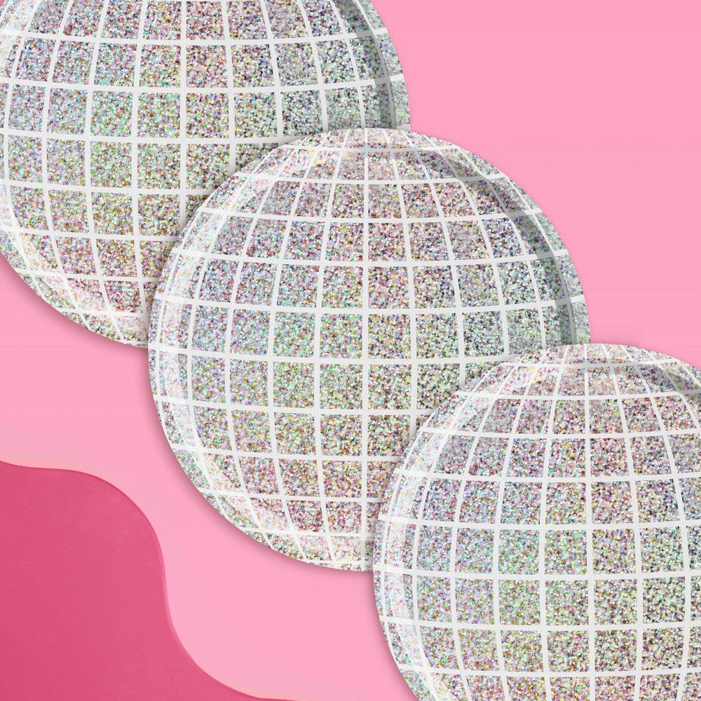 Three round, iridescent plates on a pink background