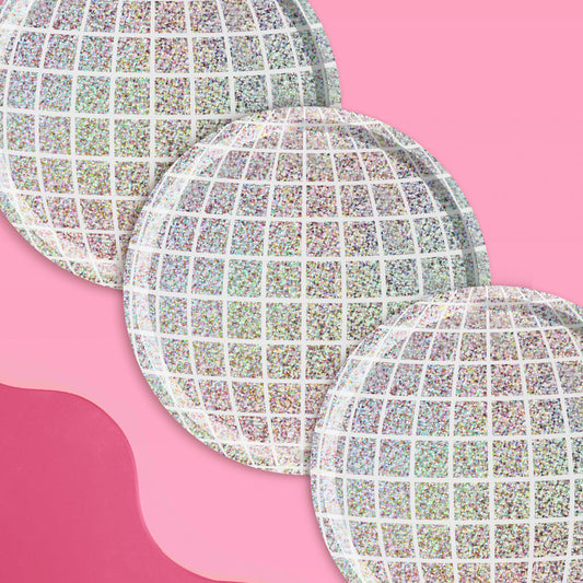 Three round, iridescent plates on a pink background