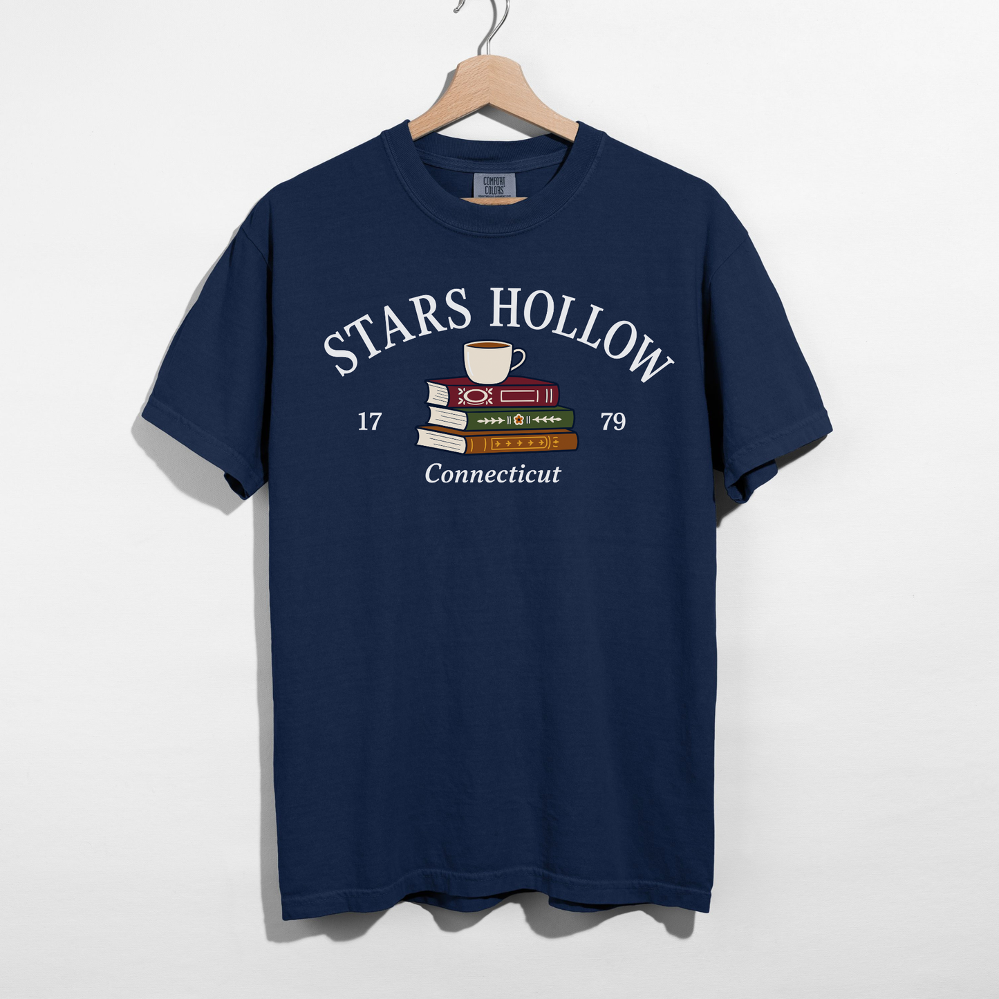 True Navy Stars Hollow Connecticut graphic t-shirt featuring stacked books and a coffee cup with vintage-inspired lettering.