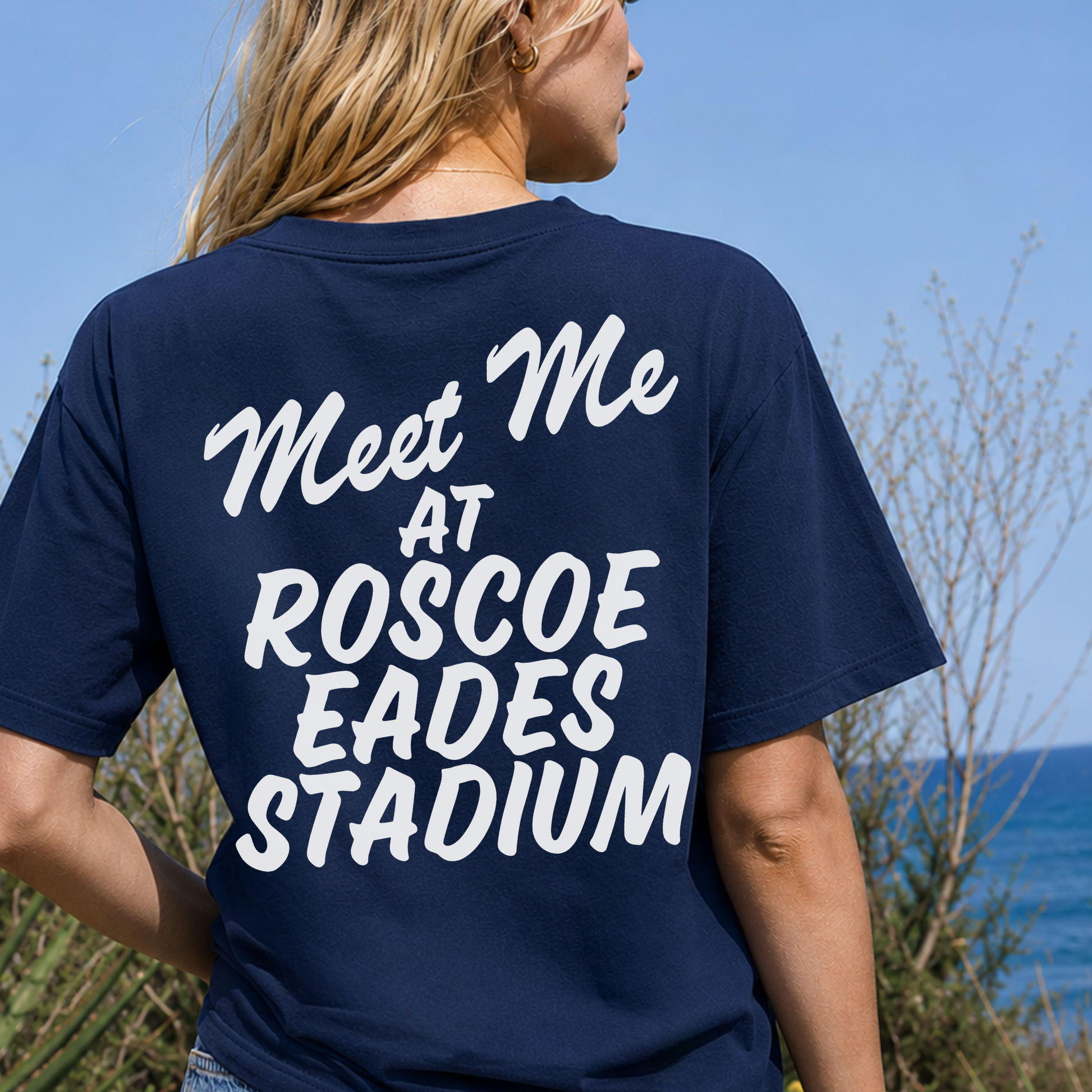 Woman wearing true navy Sterling Warriors T-shirt featuring large white Meet Me at Roscoe Eades Stadium back graphic.