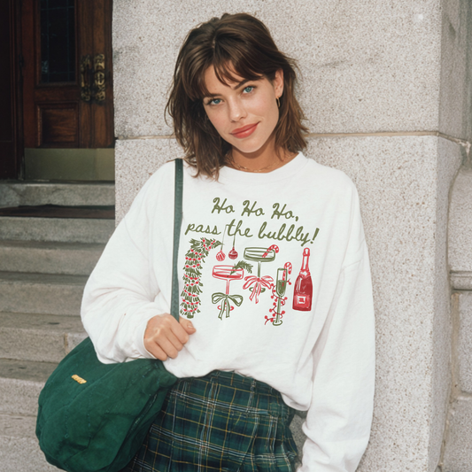 Woman in white “Ho Ho Ho, Pass the Bubbly!” sweatshirt with festive drink illustrations, smiling in front of stone steps.