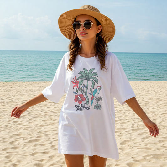 Model wearing a size Large white Rio de Janeiro tropical graphic tee on sandy beach with sun hat and sunglasses.