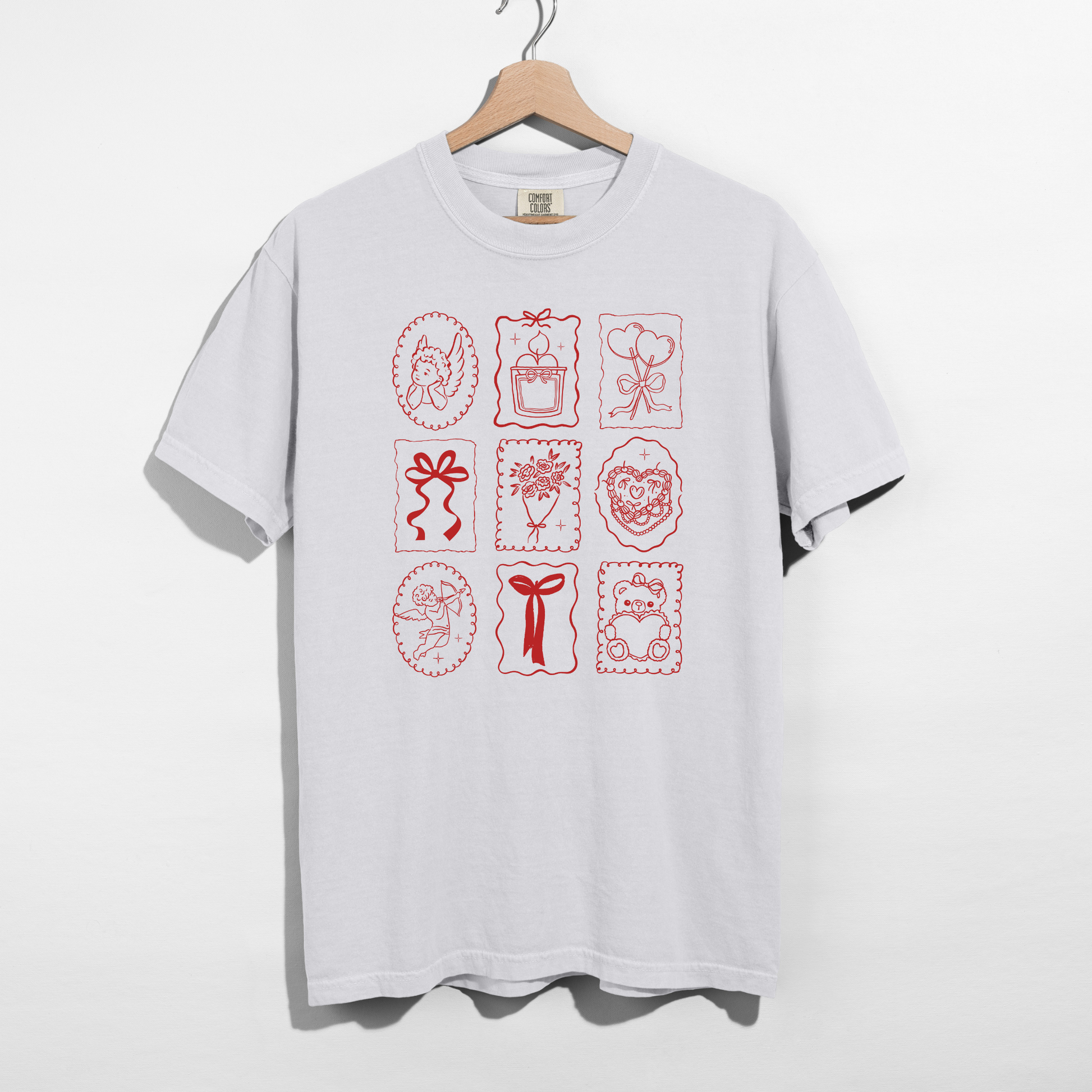 White Comfort Colors tee with red Valentine stamp icons graphic on hanger.