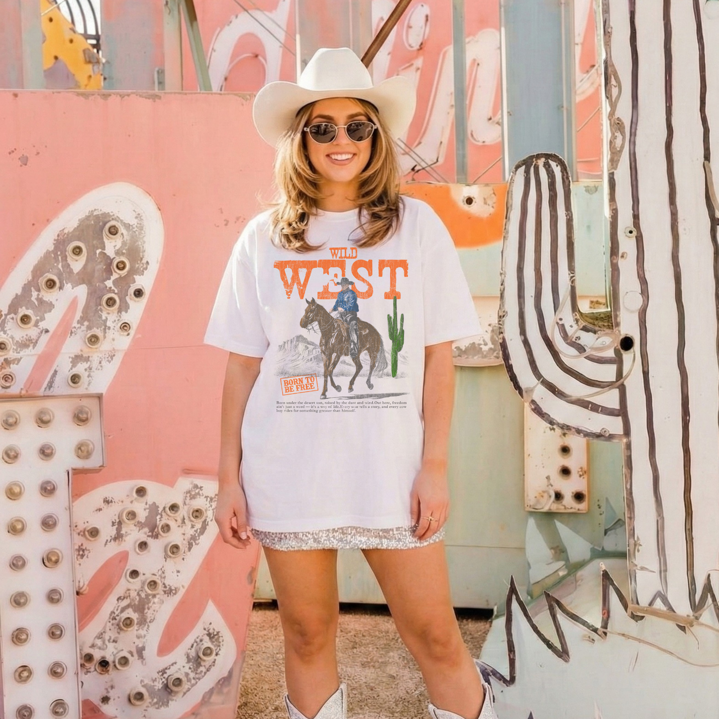 Model wearing Wild West graphic tee styled with cowboy boots and western backdrop