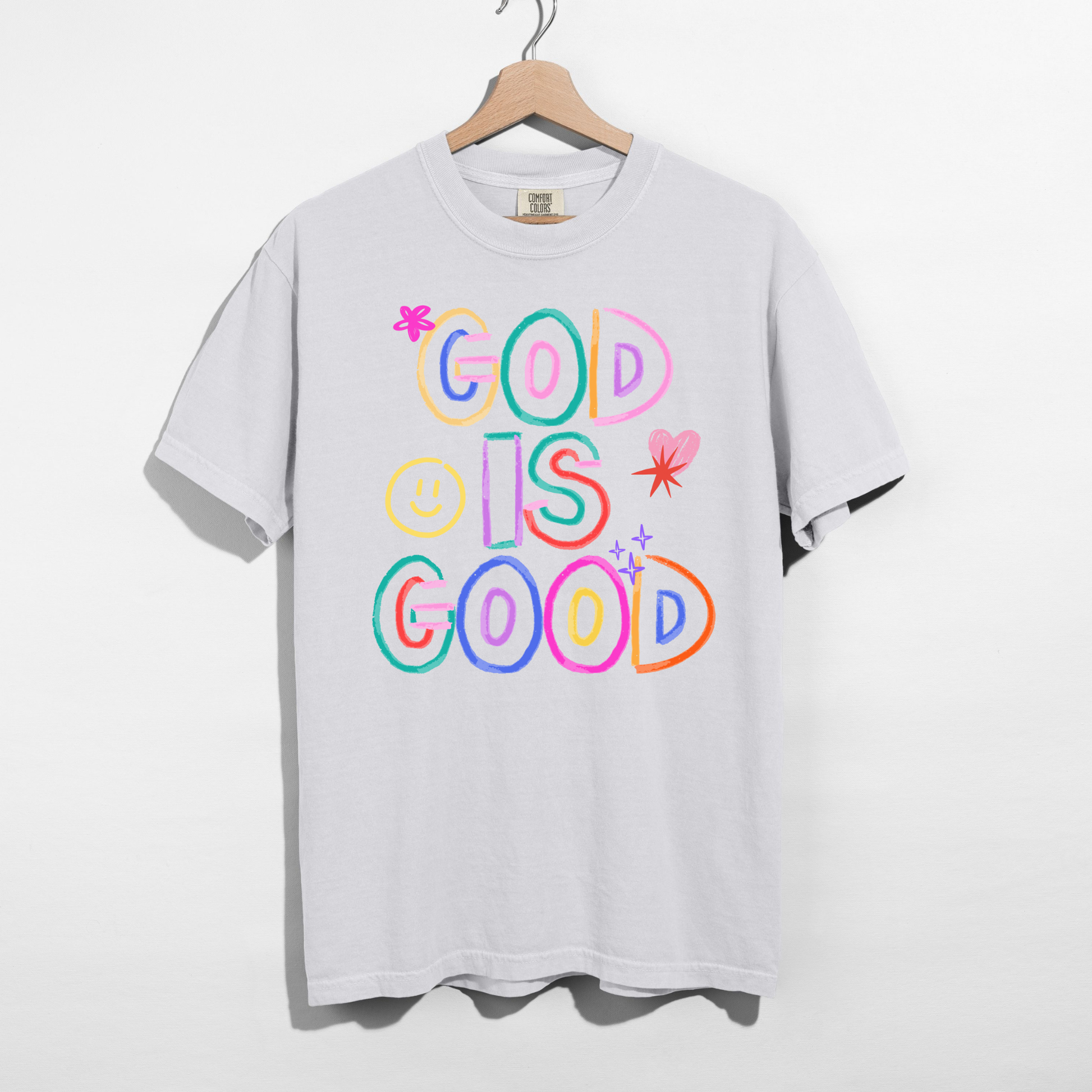 White t-shirt with 'God is Good' text in colorful letters on a hanger against a white background