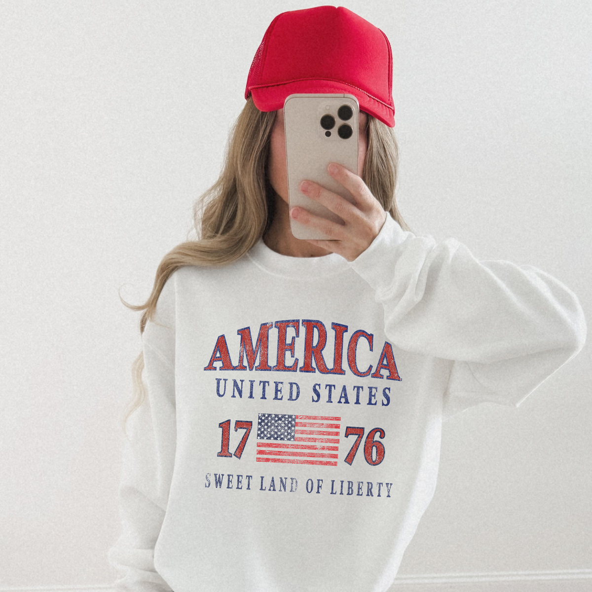 “Woman wearing America United States 1776 patriotic sweatshirt with red hat”