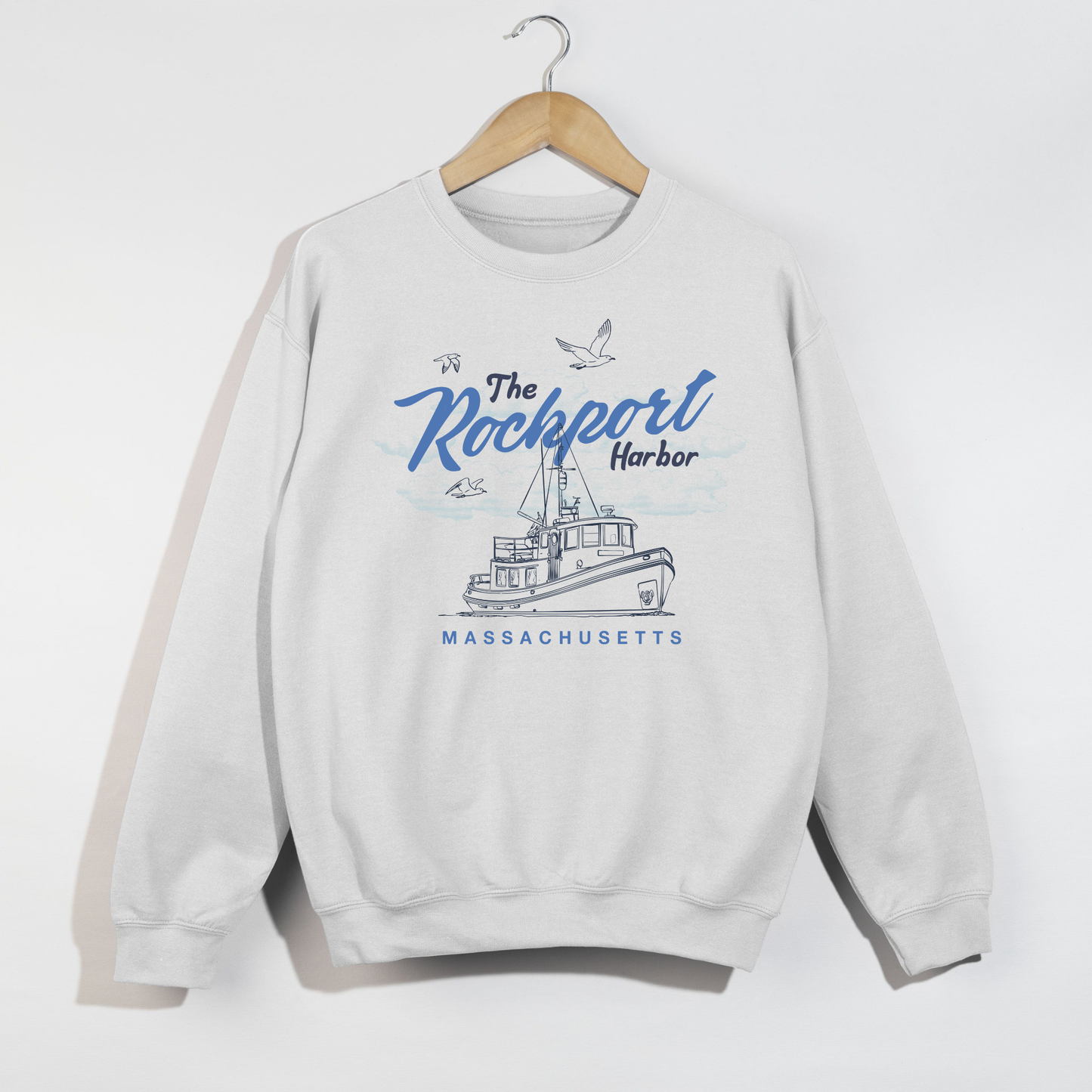 White sweatshirt with 'The Rockport Harbor, Massachusetts' design on a hanger against a white background