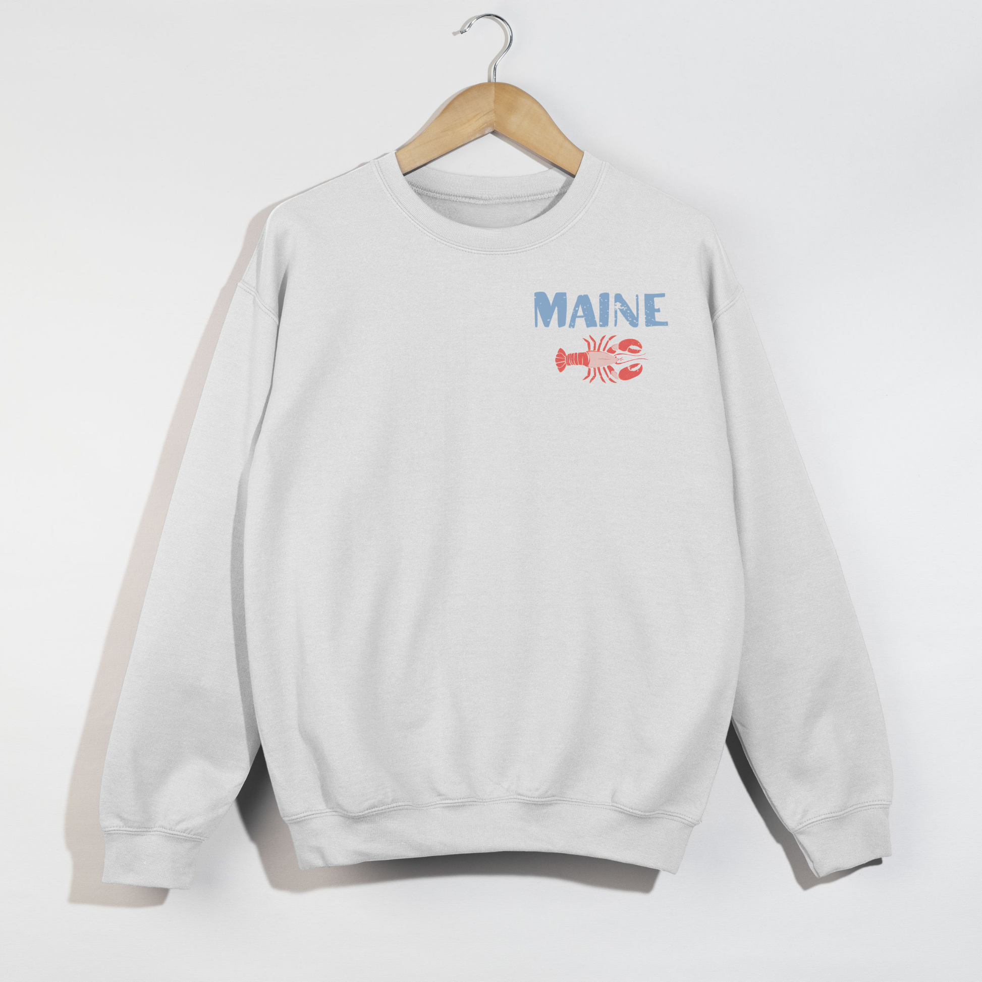 White sweatshirt with 'MAINE' and a lobster graphic on a hanger against a white background