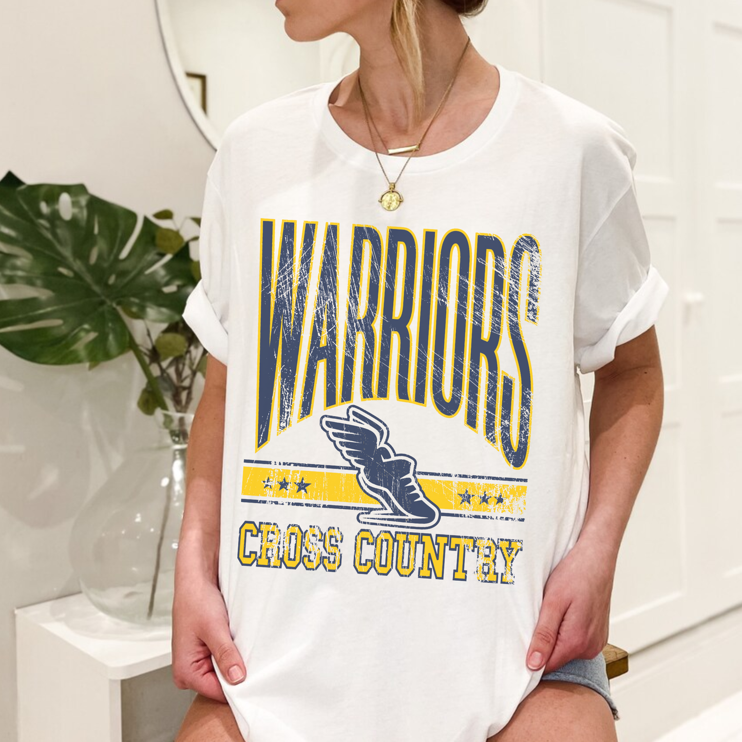 Woman wearing white Warriors Cross Country vintage unisex school spirit t-shirt with distressed athletic graphic