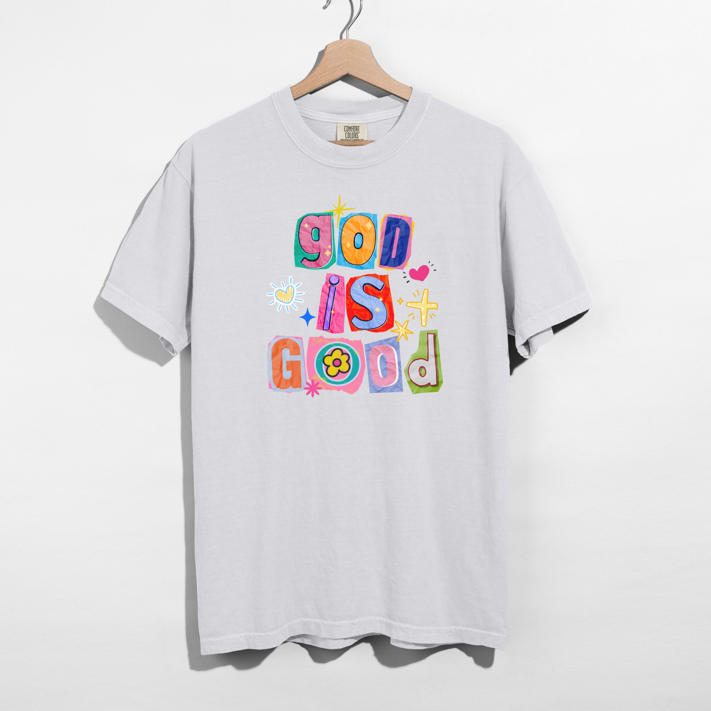White t-shirt with colorful 'God is Good' text on a hanger against a white background
