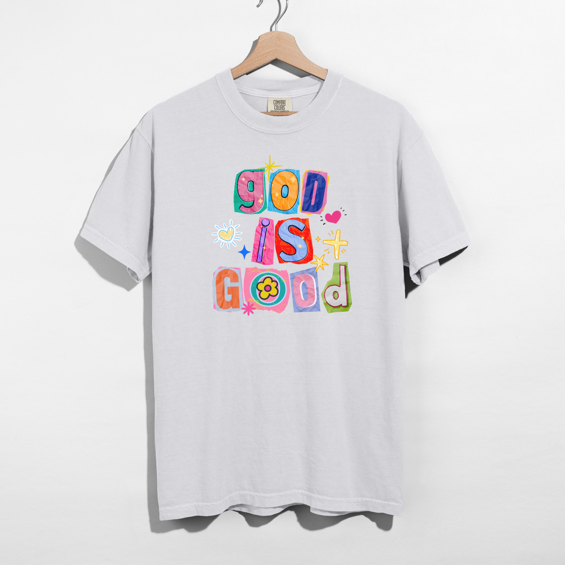 White t-shirt with colorful 'God is Good' text on a hanger against a white background