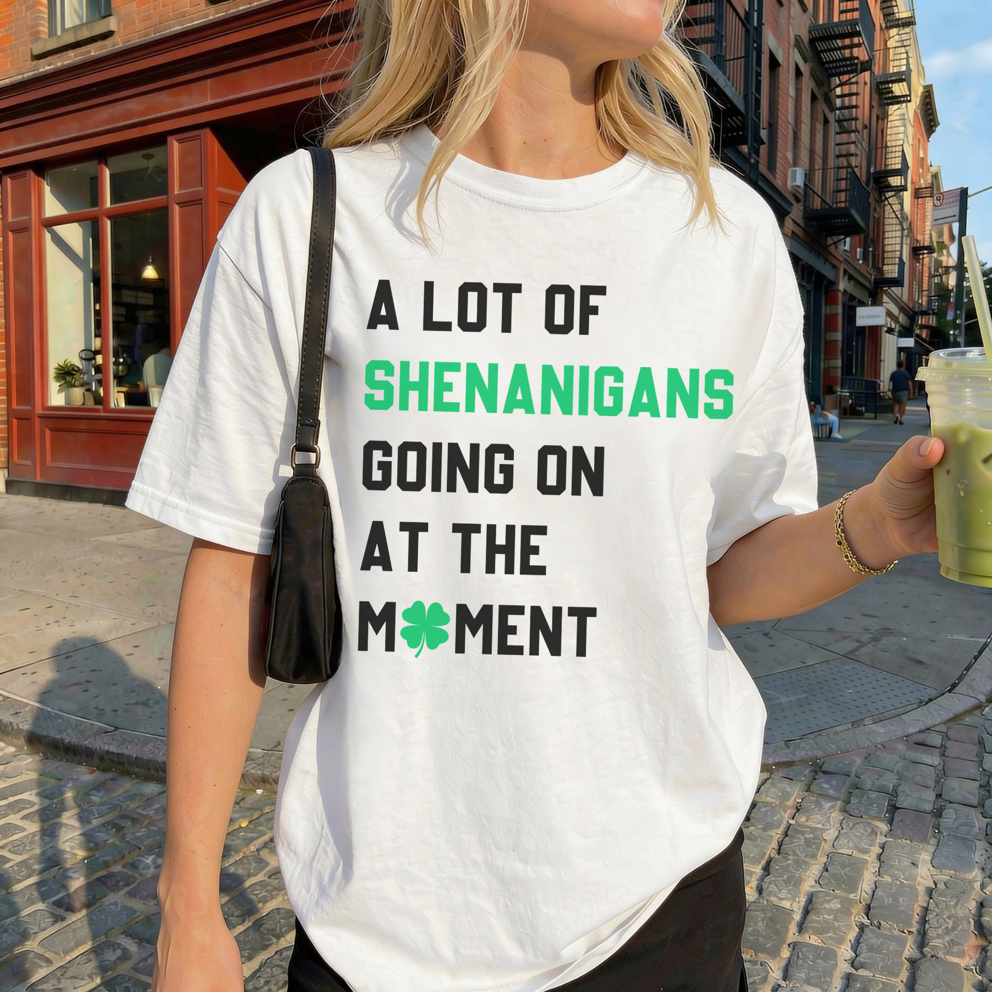 Woman wearing white A Lot of Shenanigans Going On at the Moment St Patrick’s Day graphic tee holding green iced drink