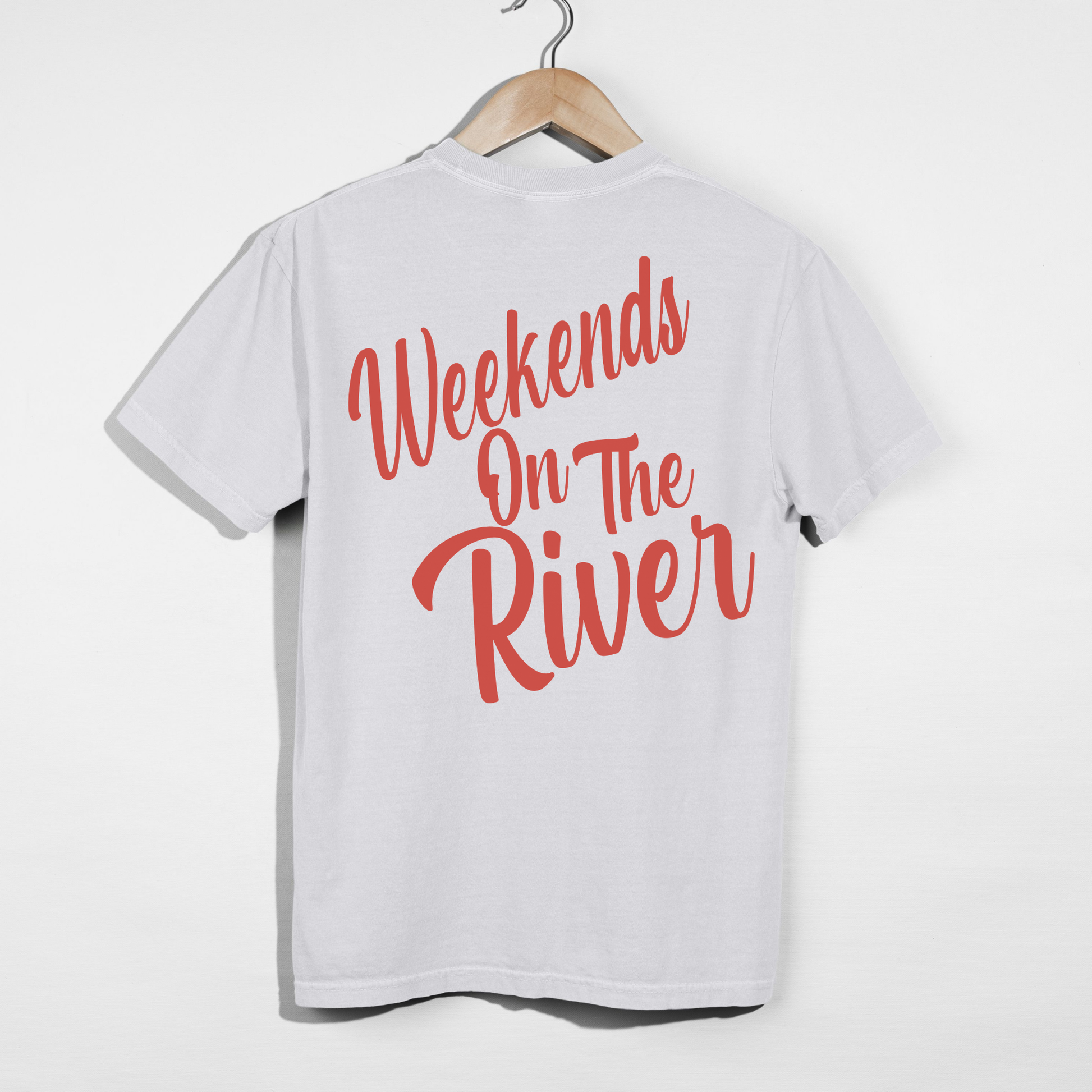 White Comfort Colors t-shirt hanging with large coral red “Weekends On The River” script graphic printed on the back.