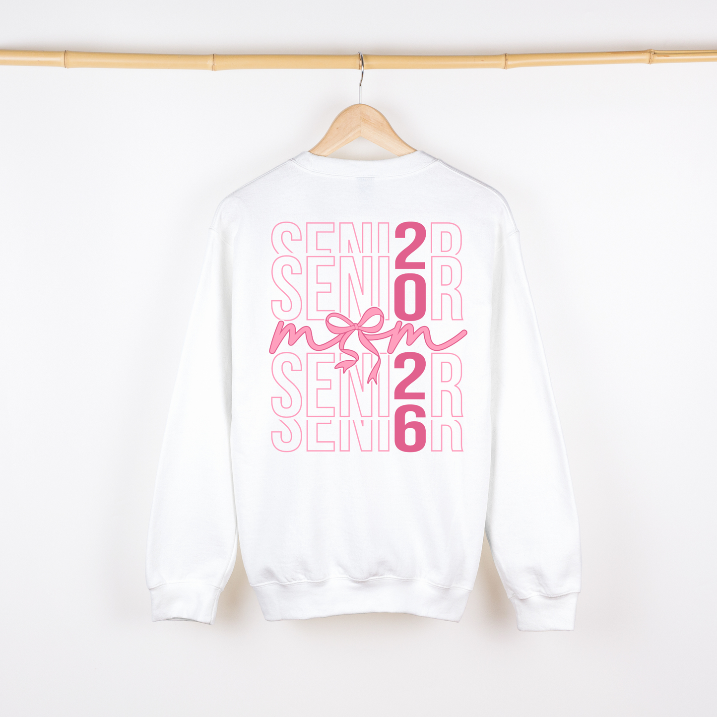 White sweatshirt with pink 'Senior 2026' text on a hanger against a white background