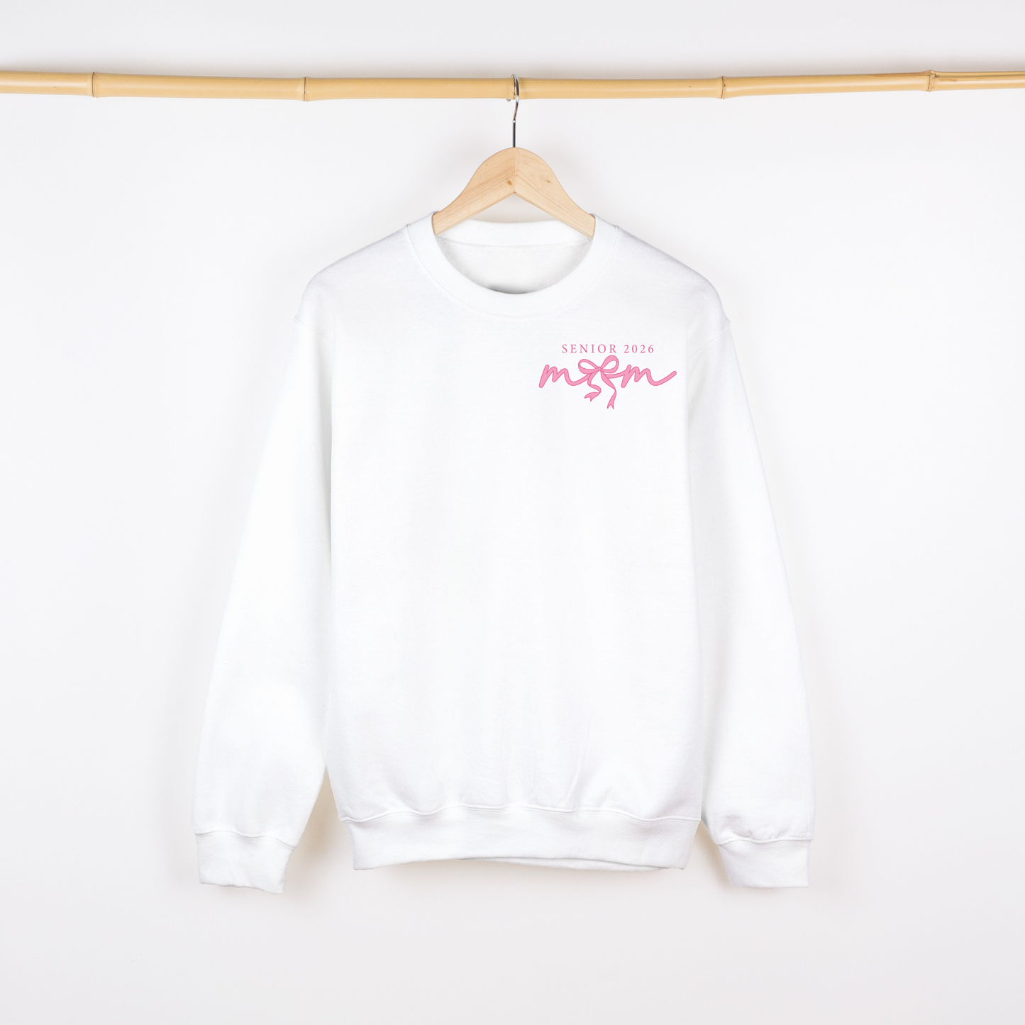 White sweatshirt with pink text on a wooden hanger against a white background