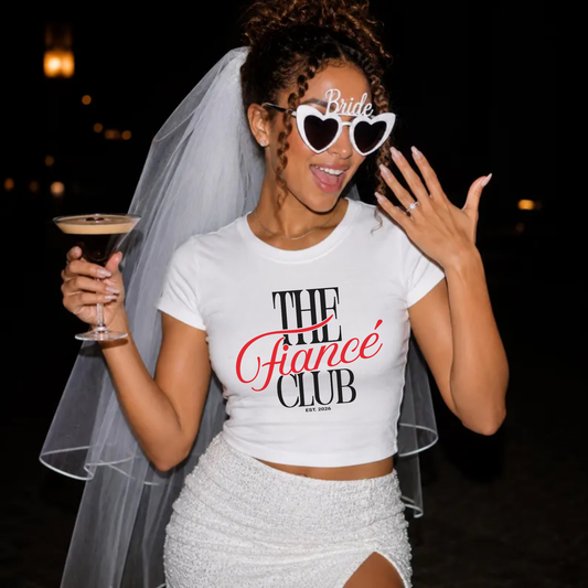 Newly engaged bride wearing The Fiancé Club Est. 2026 shirt showing engagement ring