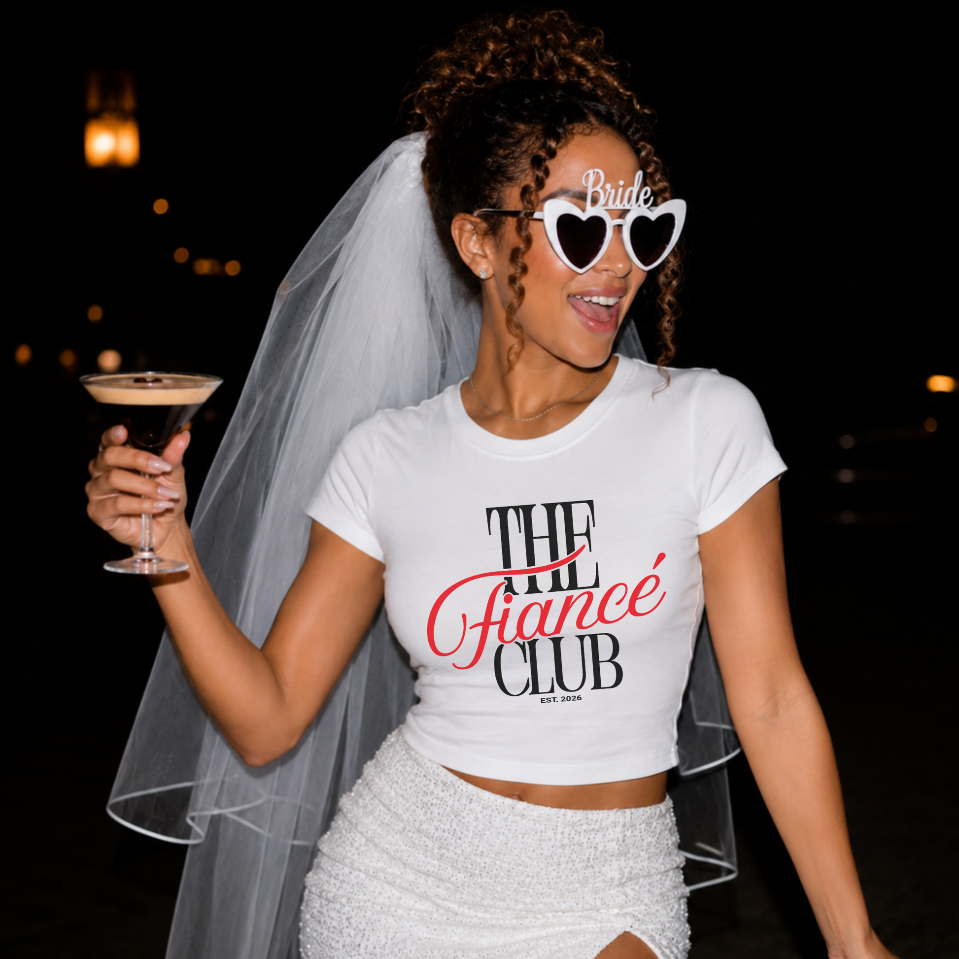 Bride-to-be wearing The Fiancé Club Est. 2026 white baby tee with veil and bride sunglasses