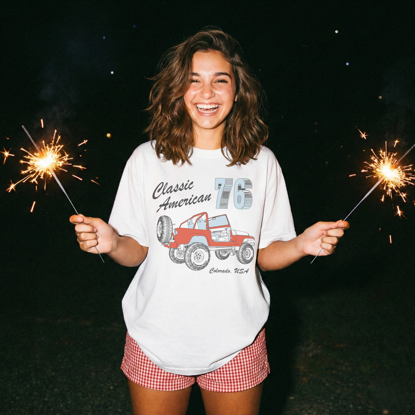 woman wearing oversized white americana jeep graphic tee holding sparklers 4th of july outfit inspiration