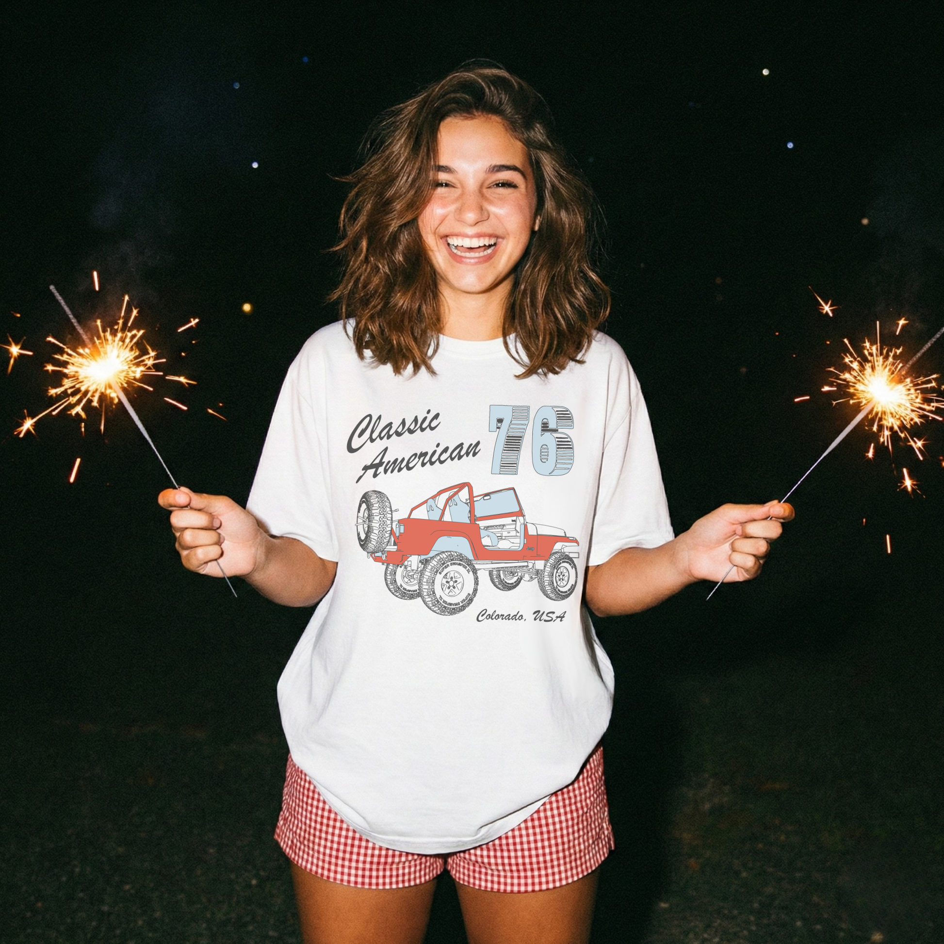 woman wearing oversized white americana jeep graphic tee holding sparklers 4th of july outfit inspiration