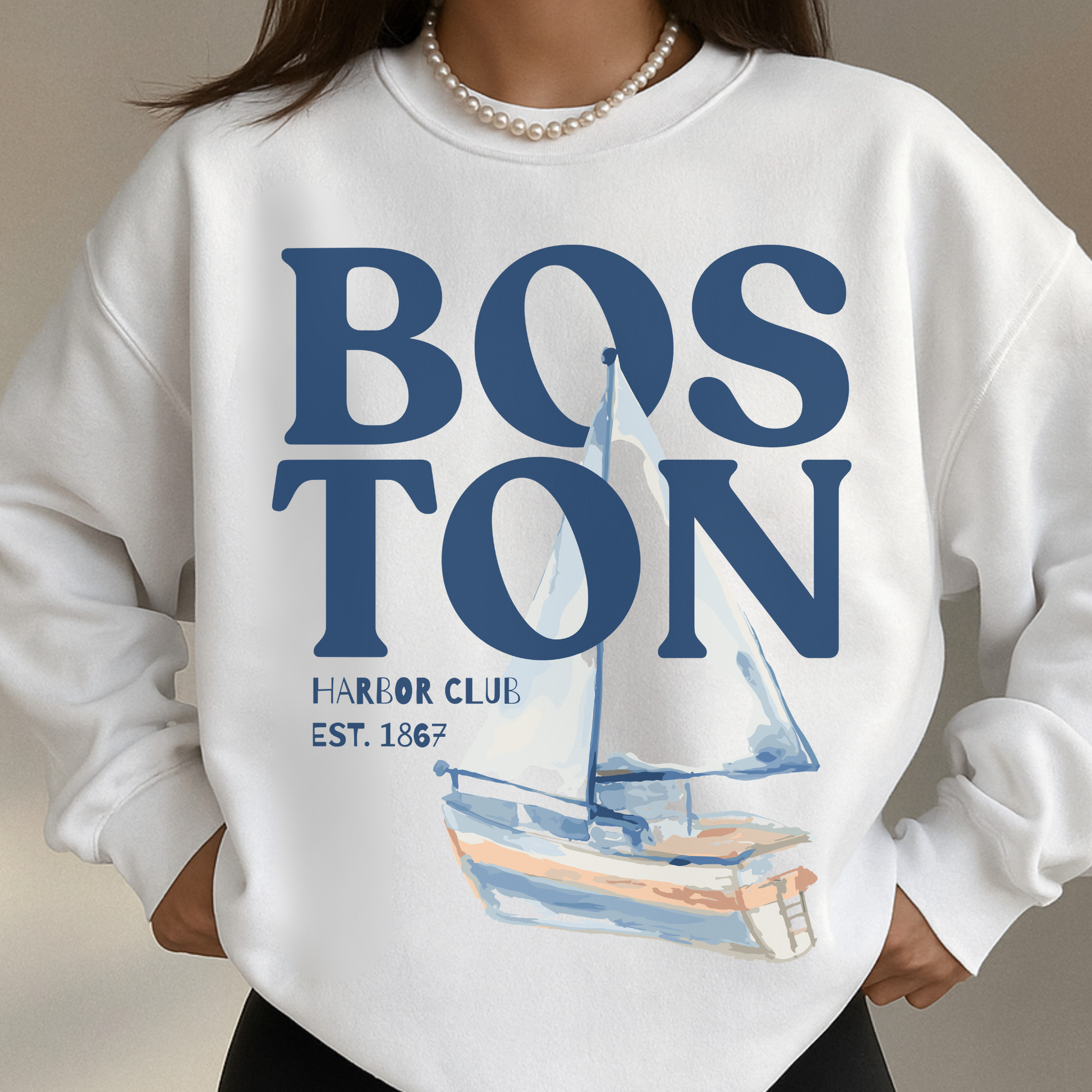 Woman wearing white Boston Harbor Club coastal sailboat sweatshirt with oversized nautical graphic and pearl necklace styling