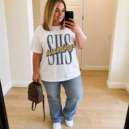 Woman wearing a white SHS Warriors graphic tee featuring distressed navy SHS lettering with gold Warriors script, styled with light wash jeans for Sterling Warriors game day.