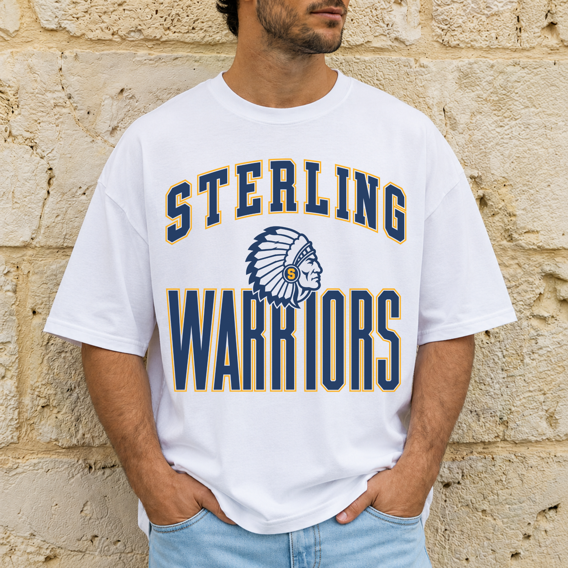 Man wearing a white Sterling Warriors mascot graphic t-shirt featuring vintage collegiate lettering and navy and gold mascot design.