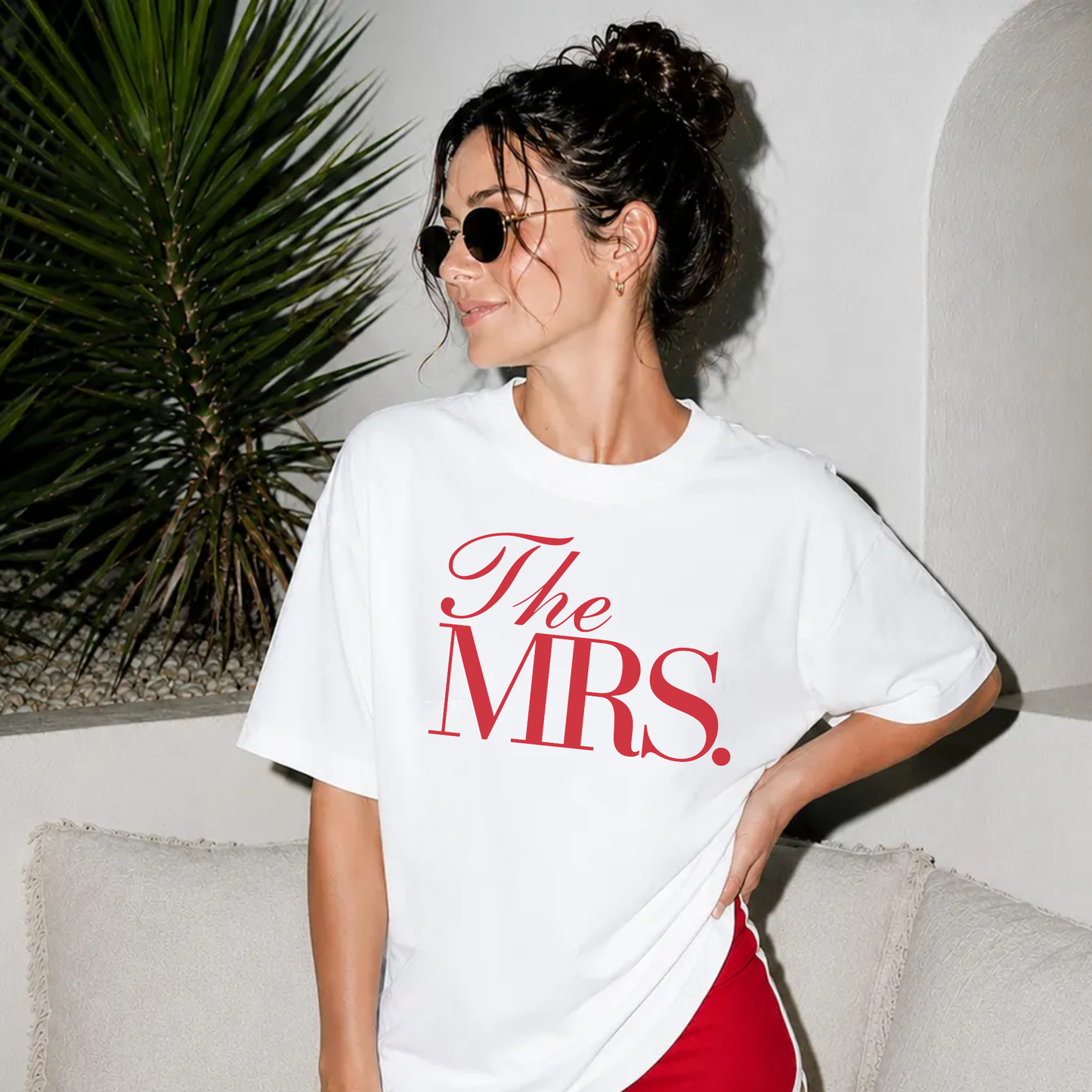 Bride wearing an oversized white The Mrs. graphic tee with elegant red lettering, styled with red athletic shorts for bridal shower, honeymoon, and wedding weekend.