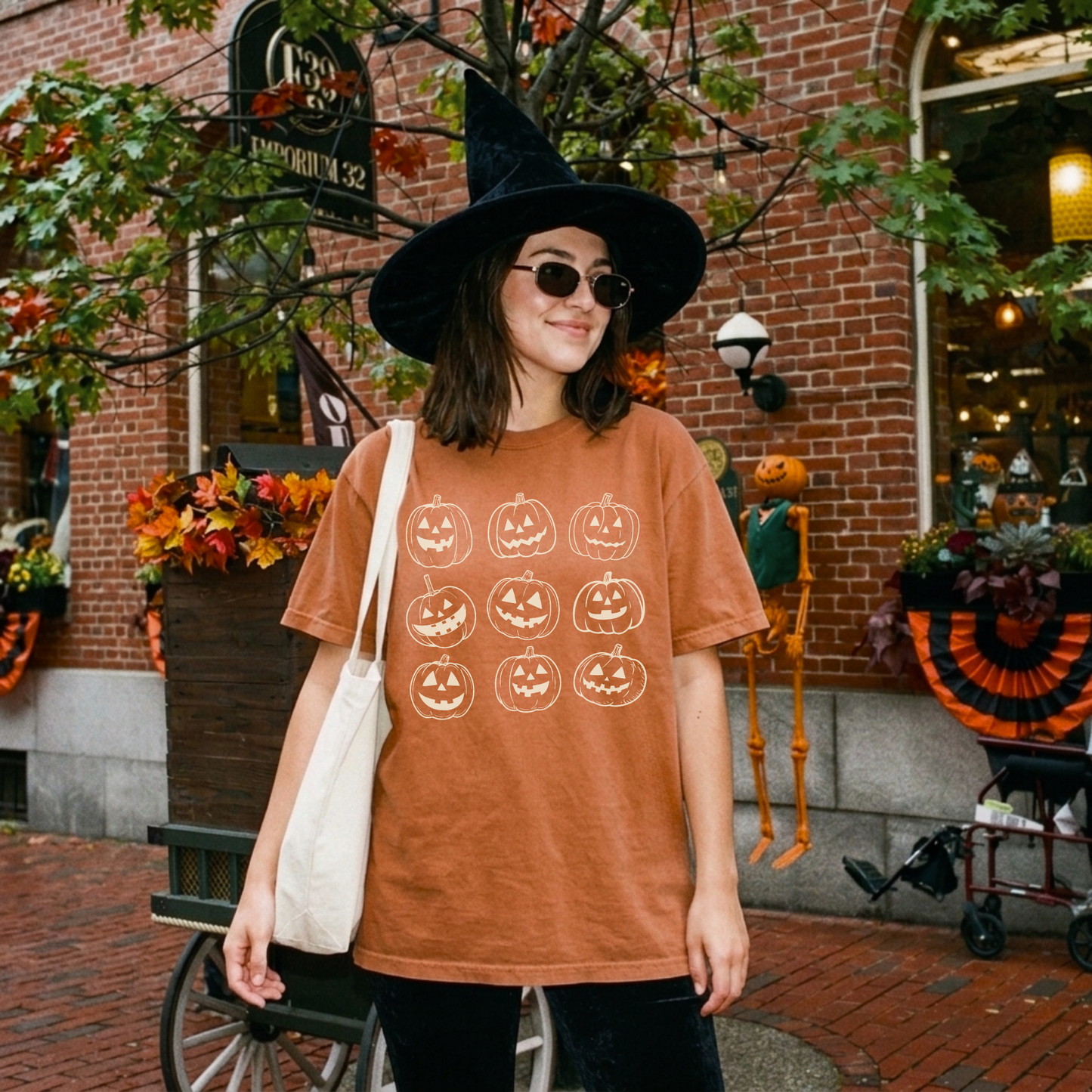 Vintage orange Comfort Colors Halloween shirt featuring nine hand drawn jack o lantern pumpkins worn in a festive fall downtown setting.