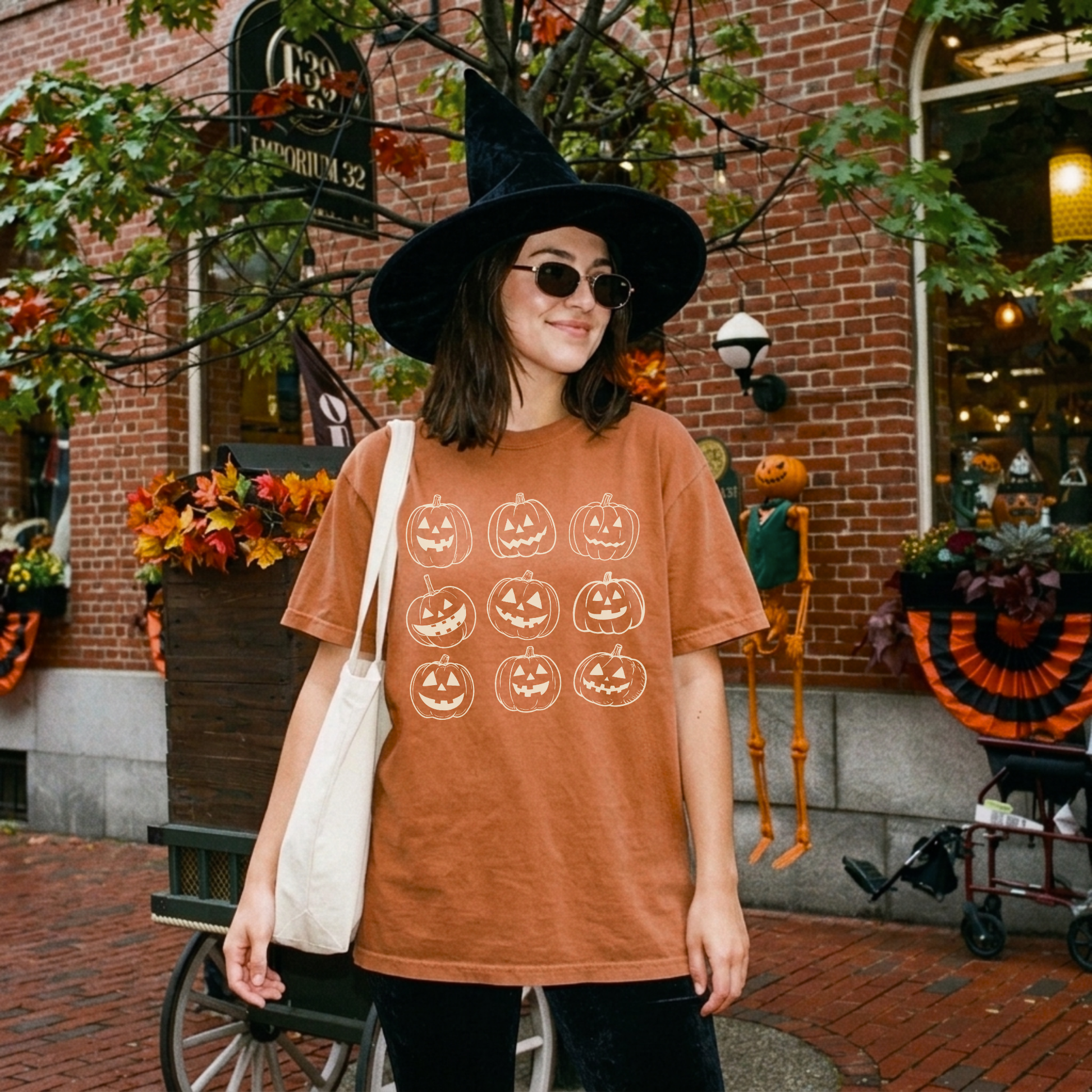 Vintage orange Comfort Colors Halloween shirt featuring nine hand drawn jack o lantern pumpkins worn in a festive fall downtown setting.