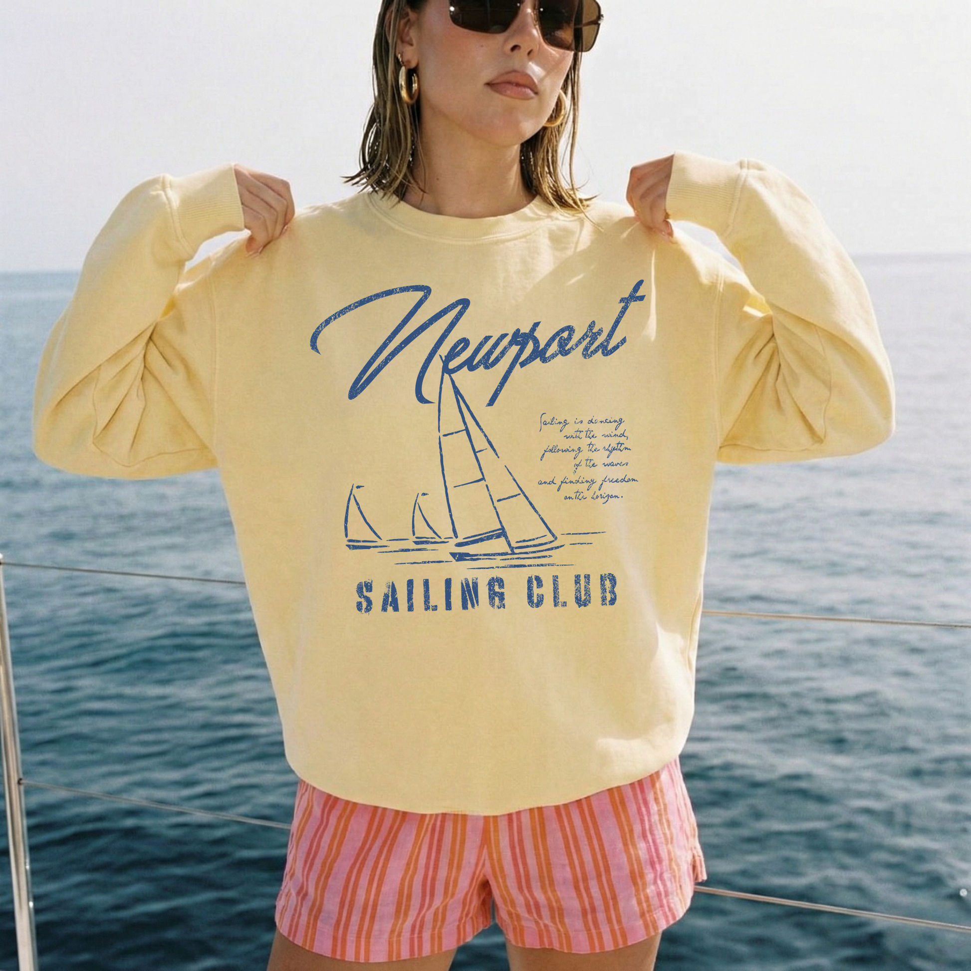 woman wearing yellow sailing club graphic sweatshirt styled with striped shorts beach vacation outfit